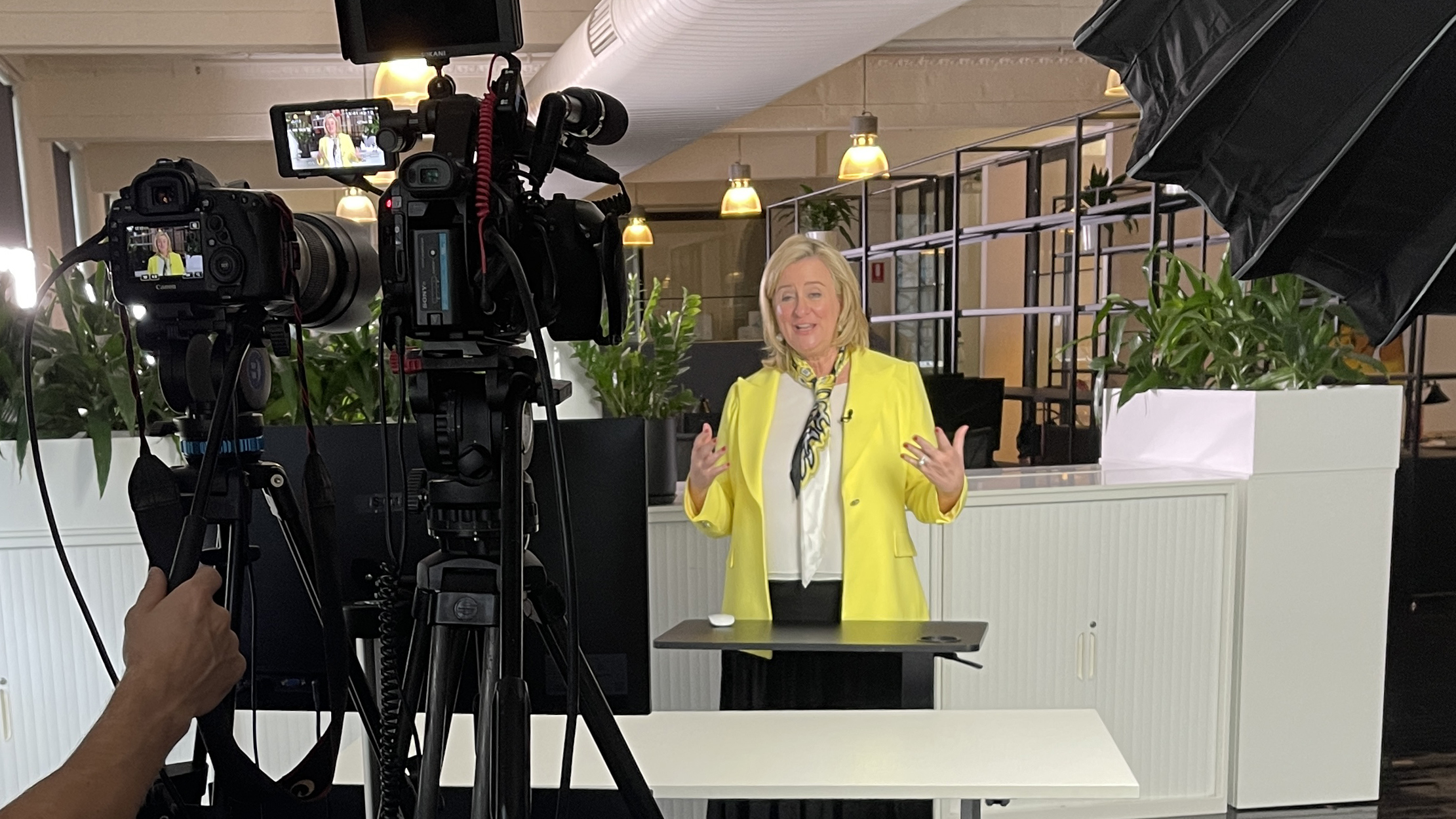 Professional woman standing behind a camera being filmed while speaking