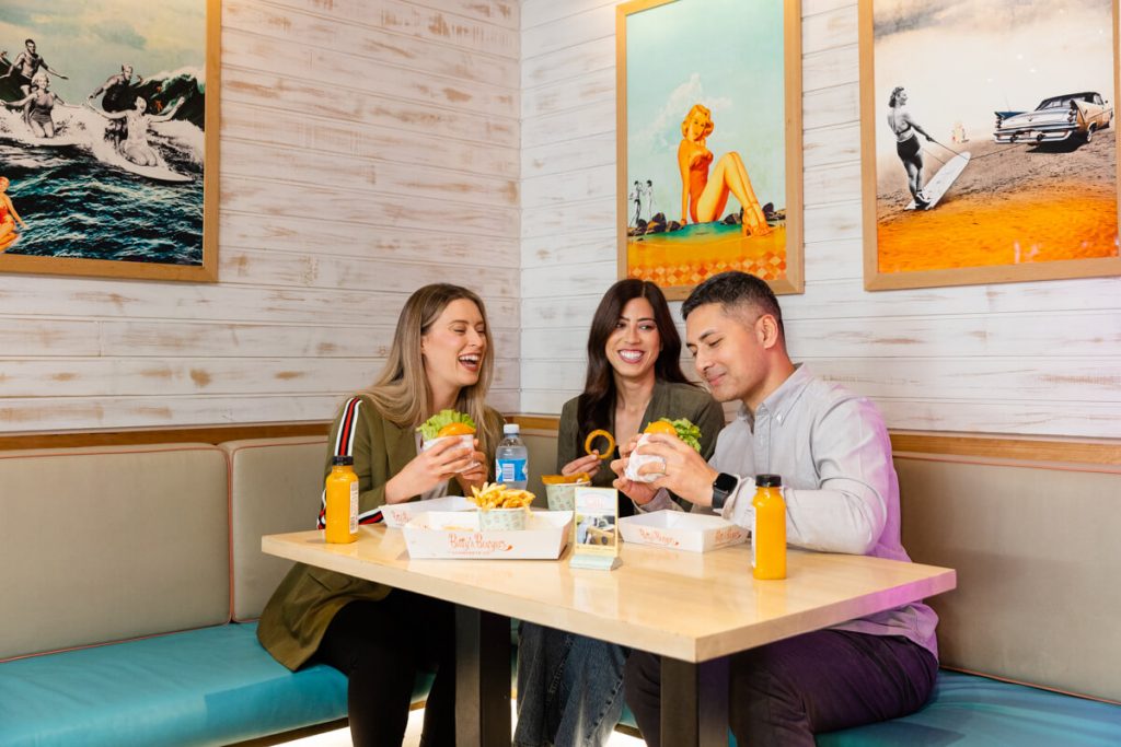 group of friends sitting at corner booth eating burgers