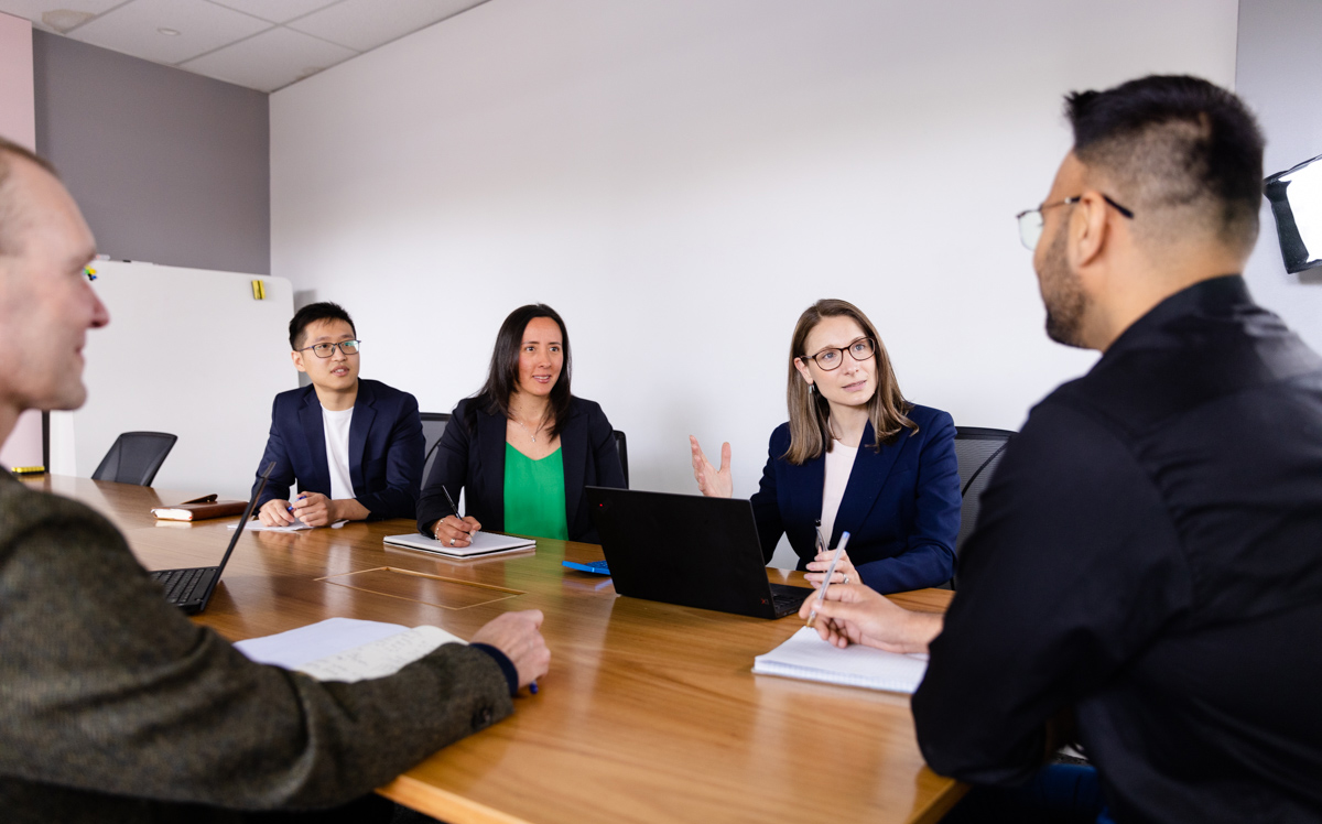 The Eligo team sitting around a boardroom table in the middle of a discussion