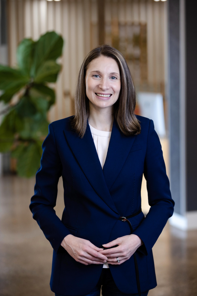 woman in blazer standing with her hands clasped in front of her