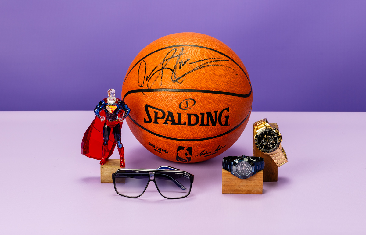 Group shot of basketball, sunglasses and two watches against a bright purple backdrop