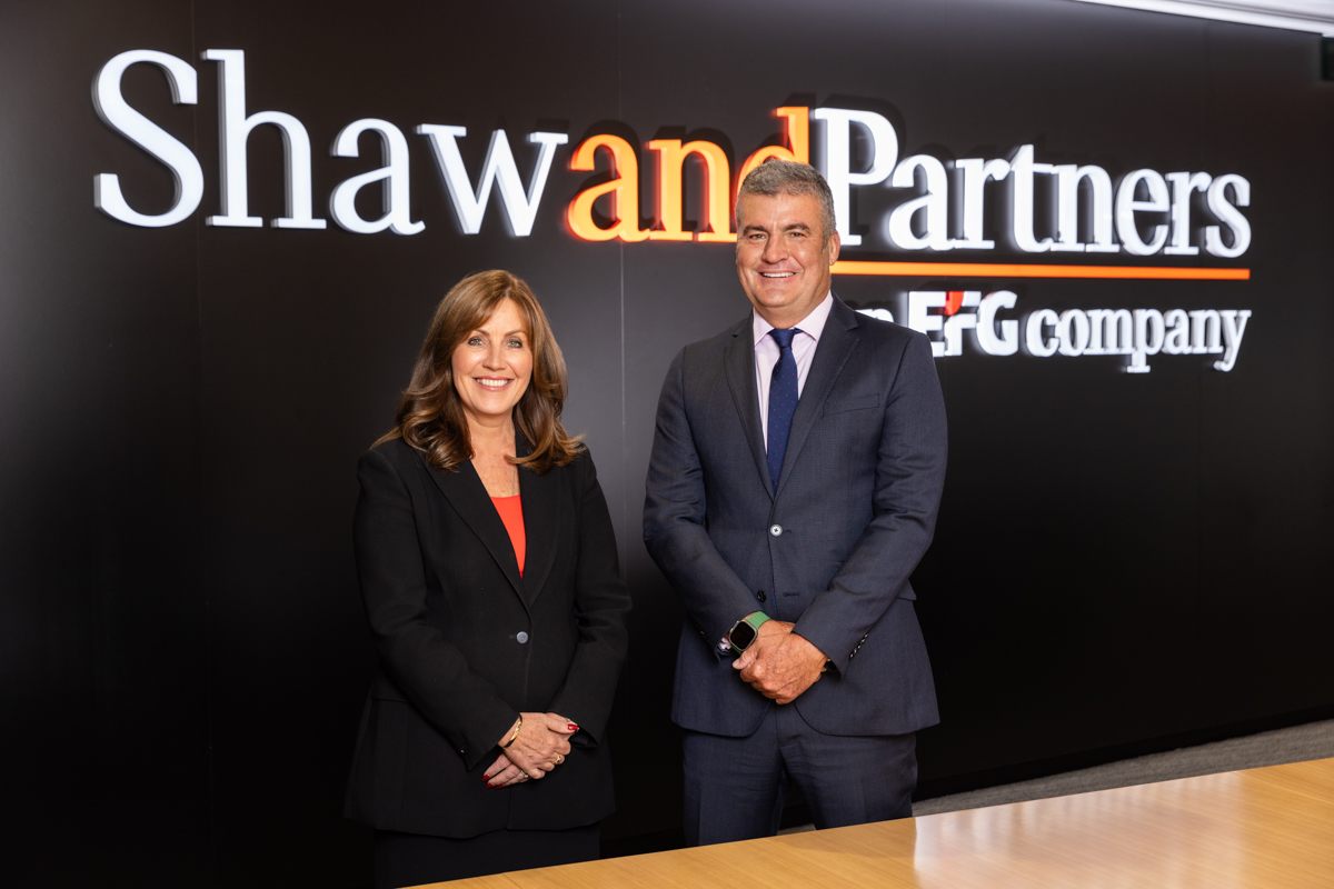 man and woman in corporate attire standing behind boardroom table