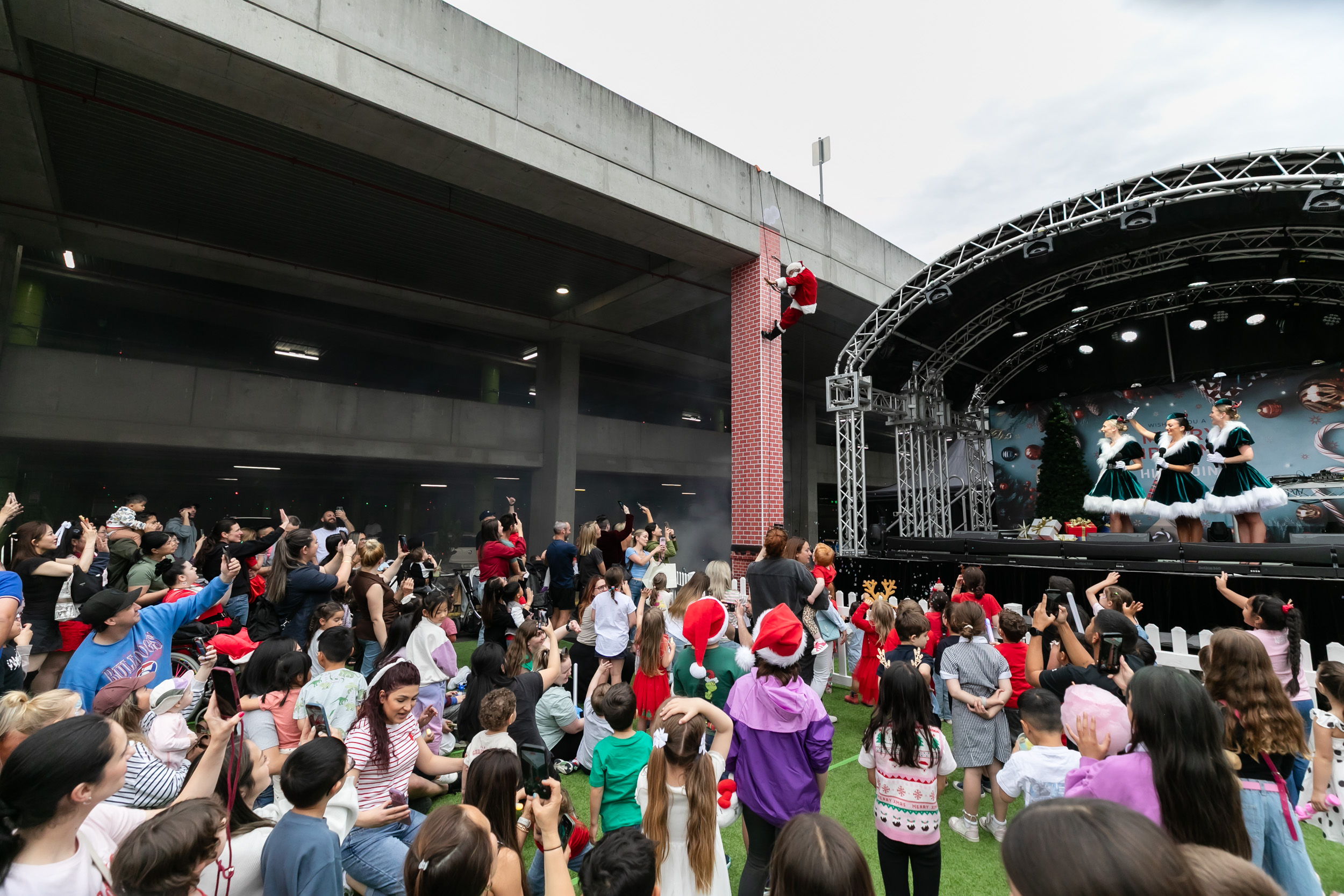 Santa abseiling into event in front of stage/crowd