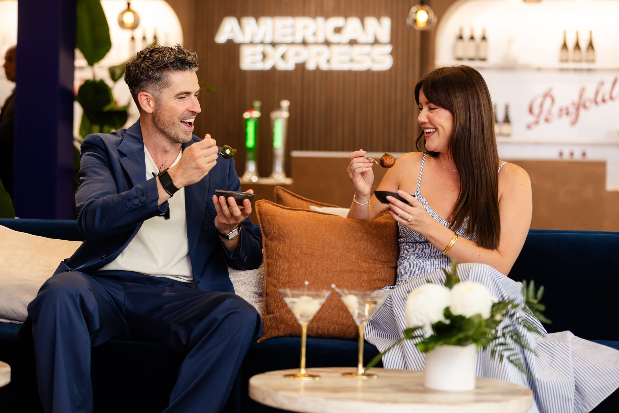 Man and woman eating at an elegant bar in front of AMEX sign