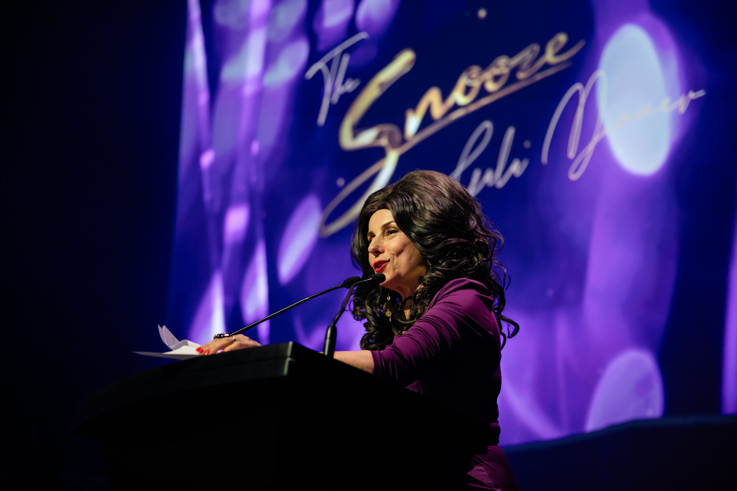 KEYSHOTS-Snooze-GALA-02Sep26-015 Comedian Effie speaking on stage at gala event